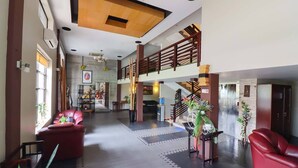 Eine großzügige Lobby mit Treppe, roten Ledersofas und modernem Design.