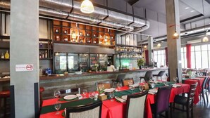 Ein Restaurant mit mehreren gedeckten Tischen, einer Bar mit Flaschenregalen und einem Rauchverbotsschild.
