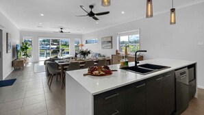 Una cocina moderna con una isla grande, armarios oscuros e iluminación colgante.