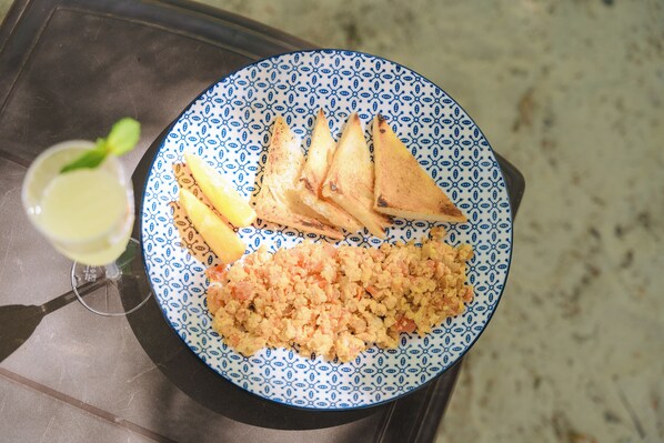 A plate with grilled sandwiches, a side of rice, and a glass of lemonade on a table.