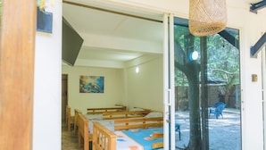 A room with a bed, wooden benches, and a painting on the wall. - Perla Negra House Hostel (Cartagena)