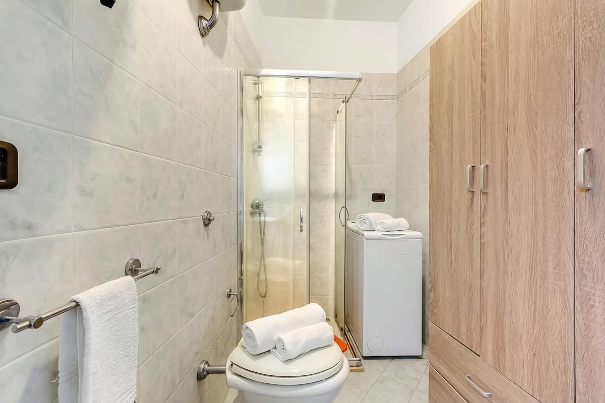 A modern bathroom with a glass shower enclosure, a toilet, and a wooden cabinet.