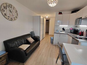 A modern kitchen with white cabinets, a black countertop, and a red kettle. - Studio rénové grand confort 3 étoiles - Résidence Les Crêtets (Les Rousses)