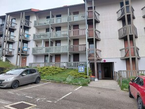 A multi-story residential building with balconies, a parking area, and a disabled access sign. - Studio rénové grand confort 3 étoiles - Résidence Les Crêtets (Les Rousses)