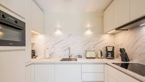 Una cocina moderna con horno empotrado, un lavamanos y una cafetera.