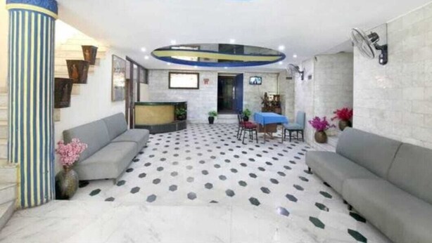 A modern interior with a patterned floor, sofas, a dining area, and a staircase.