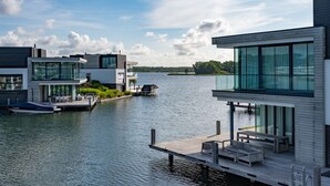A modern waterfront property with a dock, a boat, and a glass-enclosed building. - Dormio Harbour Village (Arnemuiden)