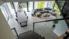 A spacious living area with a large gray sectional sofa, a dining table with chairs, and a staircase leading to an upper floor. - Dormio Harbour Village (Arnemuiden)