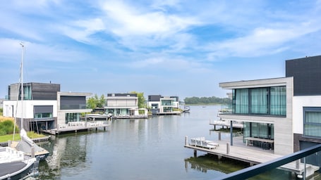 A modern waterfront property with multiple docked boats, a clear sky, and contemporary architecture.