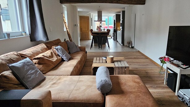 A spacious living room with a large sofa, a coffee table, and a flat-screen TV. - Like at Home: Apartment near the forest with office and terrace (Liège)