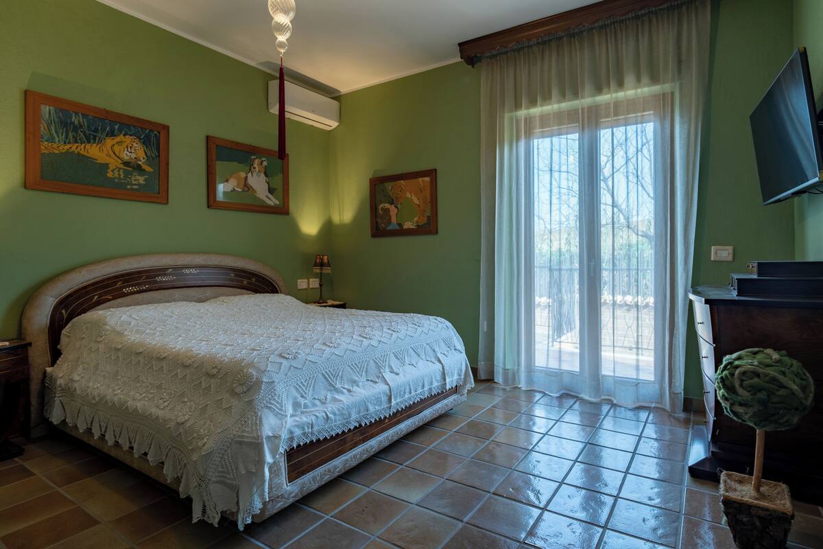 A bedroom with a bed, a television, and artwork on the walls.