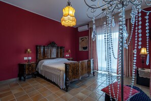 Une chambre à coucher avec un lit en bois, un lustre et un mur rouge.