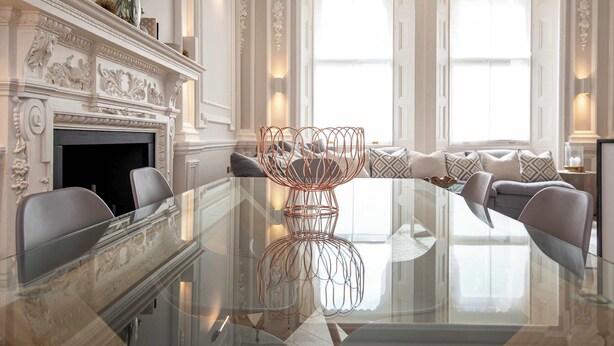 Una habitación lujosa con una mesa de vidrio, una chimenea elegante y un rincón de estar cómodo.