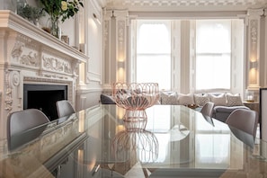 A luxurious room with a glass table, elegant fireplace, and a comfortable seating area.