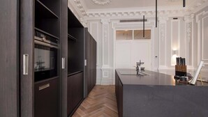 Cocina moderna con armarios oscuros, suelo de madera en espiga e isla central.