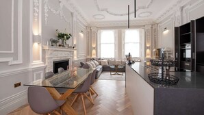 Un amplio salón con mesa de comedor de cristal, sofás y chimenea.