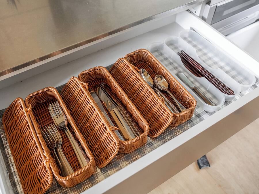 A drawer with wicker baskets containing cutlery.