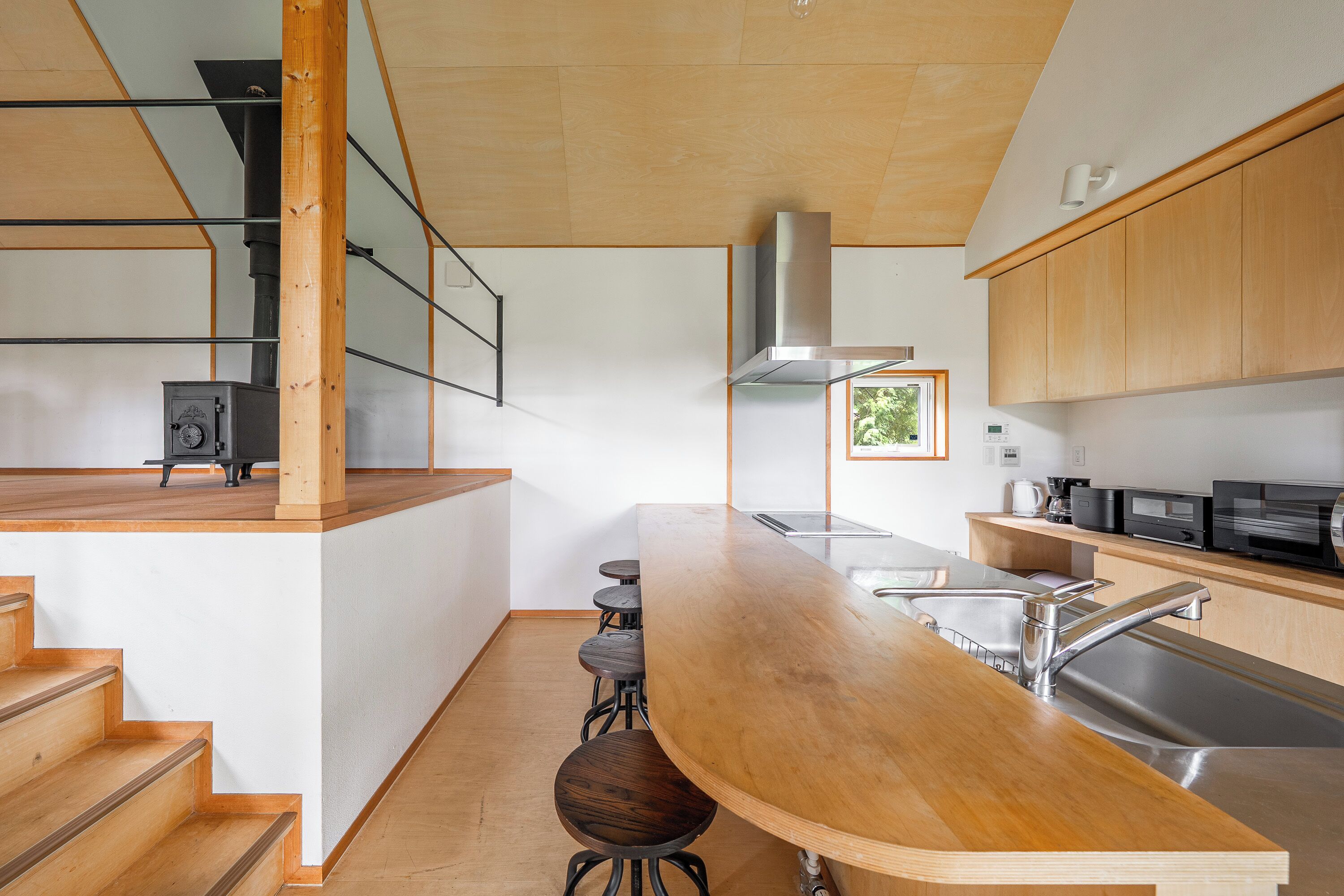 A modern kitchen with a wooden bar, stainless steel appliances, and a built-in stove.