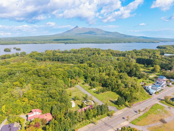 Un quartier résidentiel avec des maisons, une route et un lac, avec une montagne en arrière-plan.