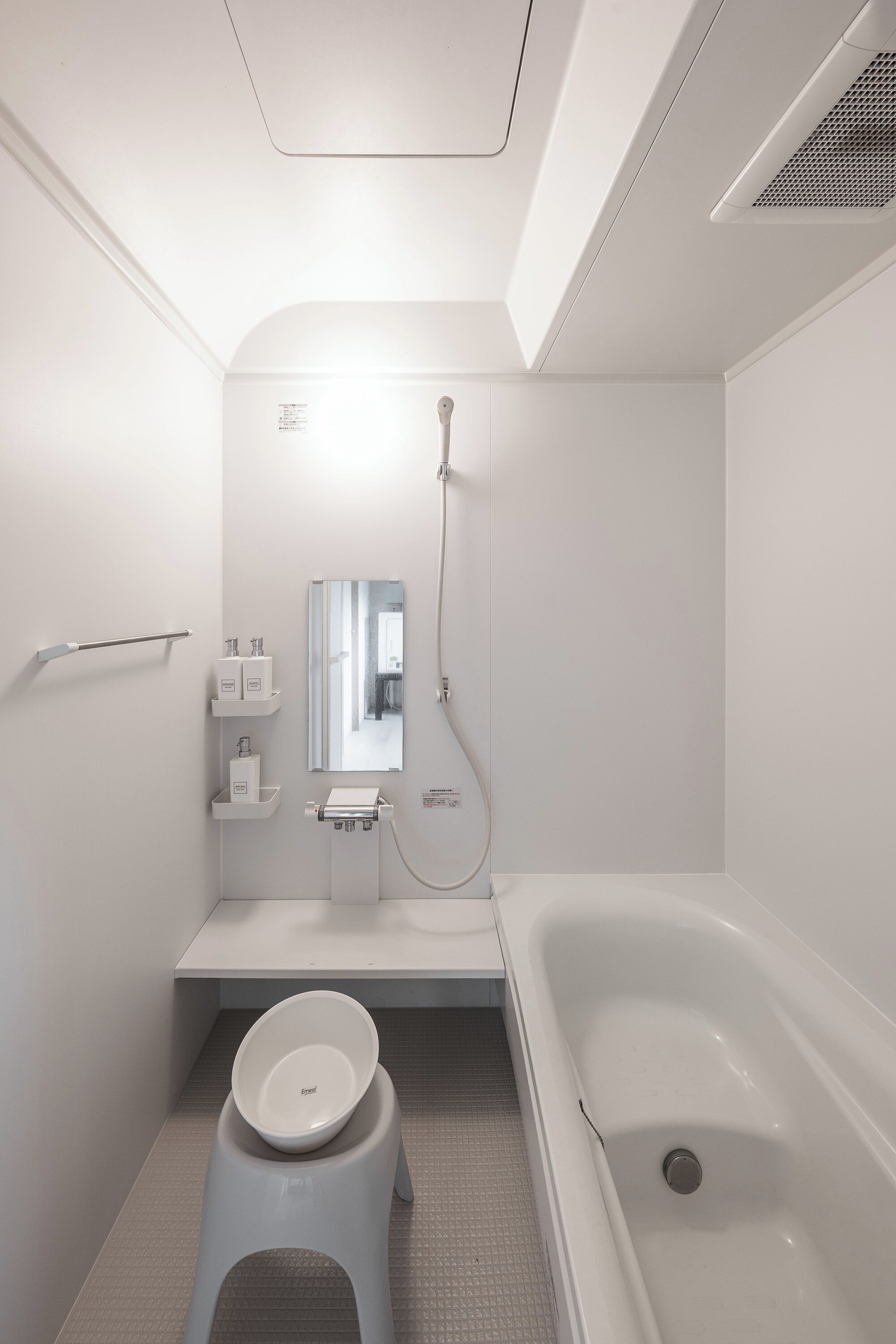 A modern bathroom with a toilet, sink, mirror, and bathtub.