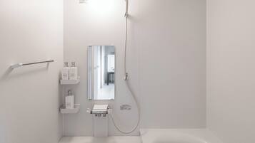 A modern bathroom with a toilet, sink, mirror, and bathtub.