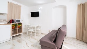 A modern, well-lit room with a sofa, a small table, a TV mounted on the wall, and a microwave on the counter. - Mifra n 1 in Bari With 1 Bedrooms and 1 Bathrooms (Bari)