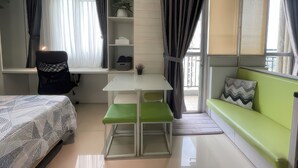 Ein kompakter, moderner Raum mit einem Bett, einem Schreibtisch, einer grünen Bank und einem Sofa.