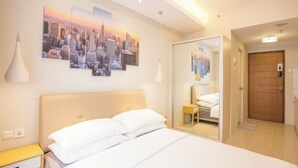 Ein Hotelzimmer mit einem großen Bett, einem Nachttisch, einem Spiegel und einem Stadtbild an der Wand.