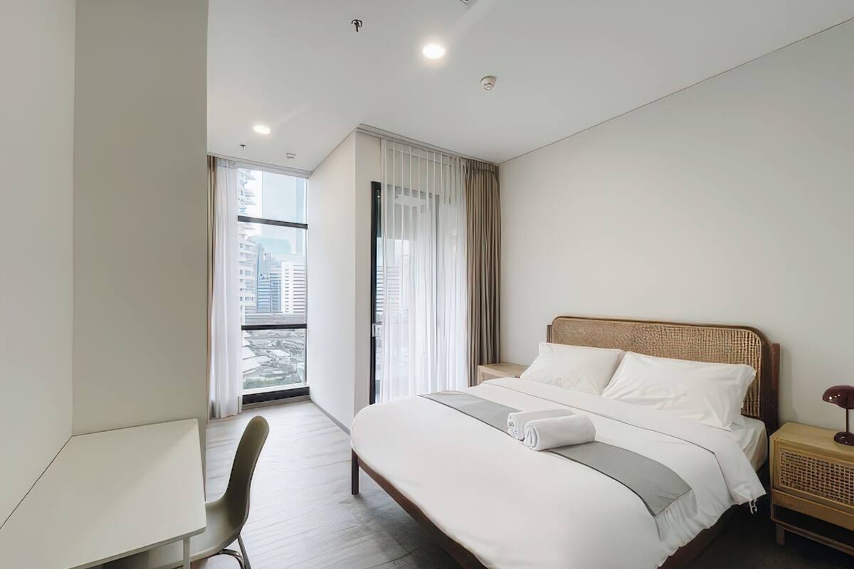 Quarto de hotel moderno com uma cama grande, uma escrivaninha e uma cadeira.