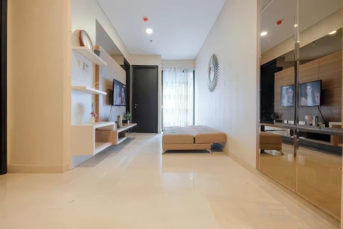 Una sala de estar moderna con sofá, televisor y mueble de entretenimiento.
