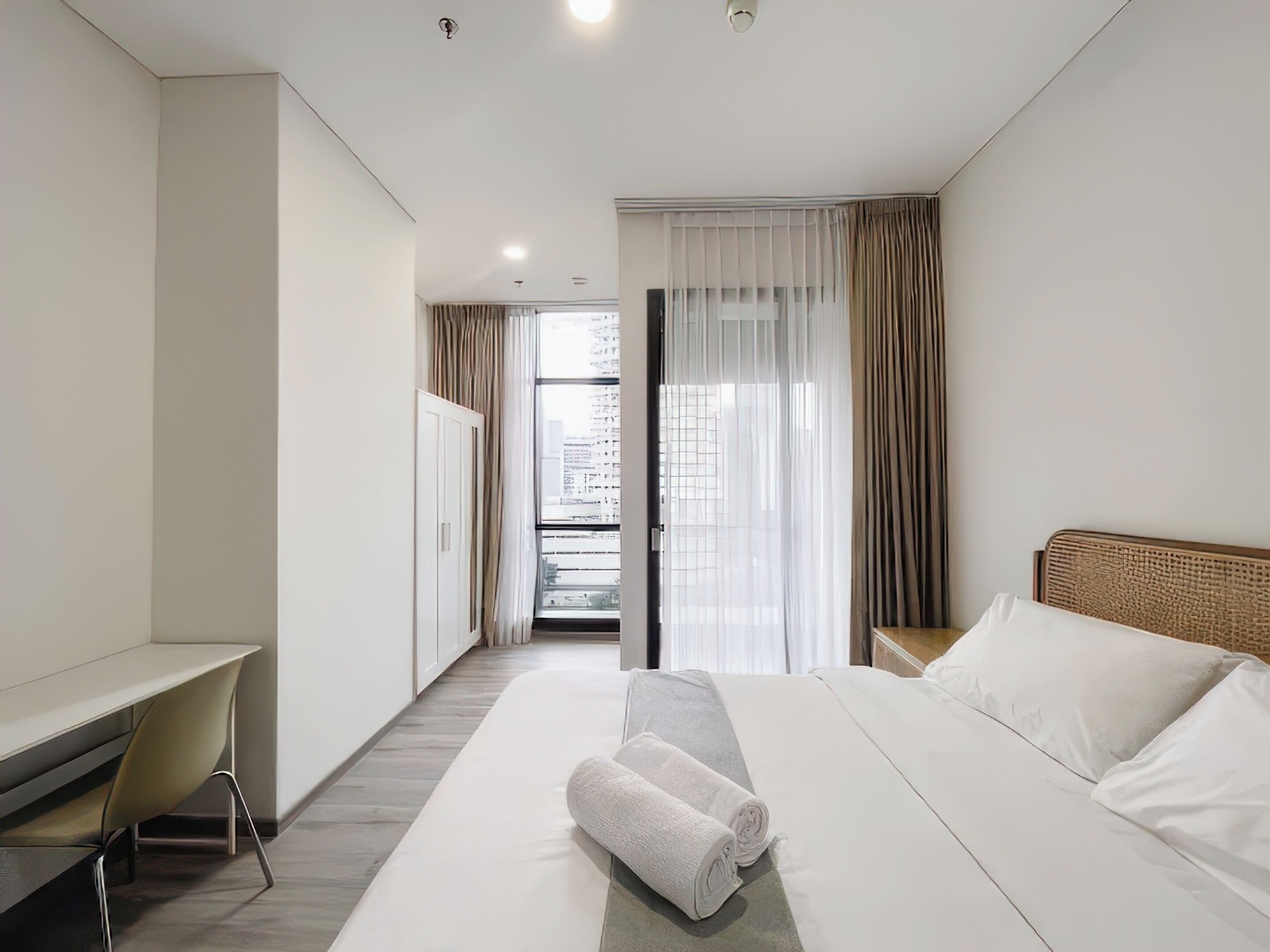 Habitación de hotel moderna con cama, escritorio y vistas a la ciudad a través del ventanal.