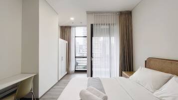 Habitación de hotel moderna con cama, escritorio y vistas a la ciudad a través del ventanal.