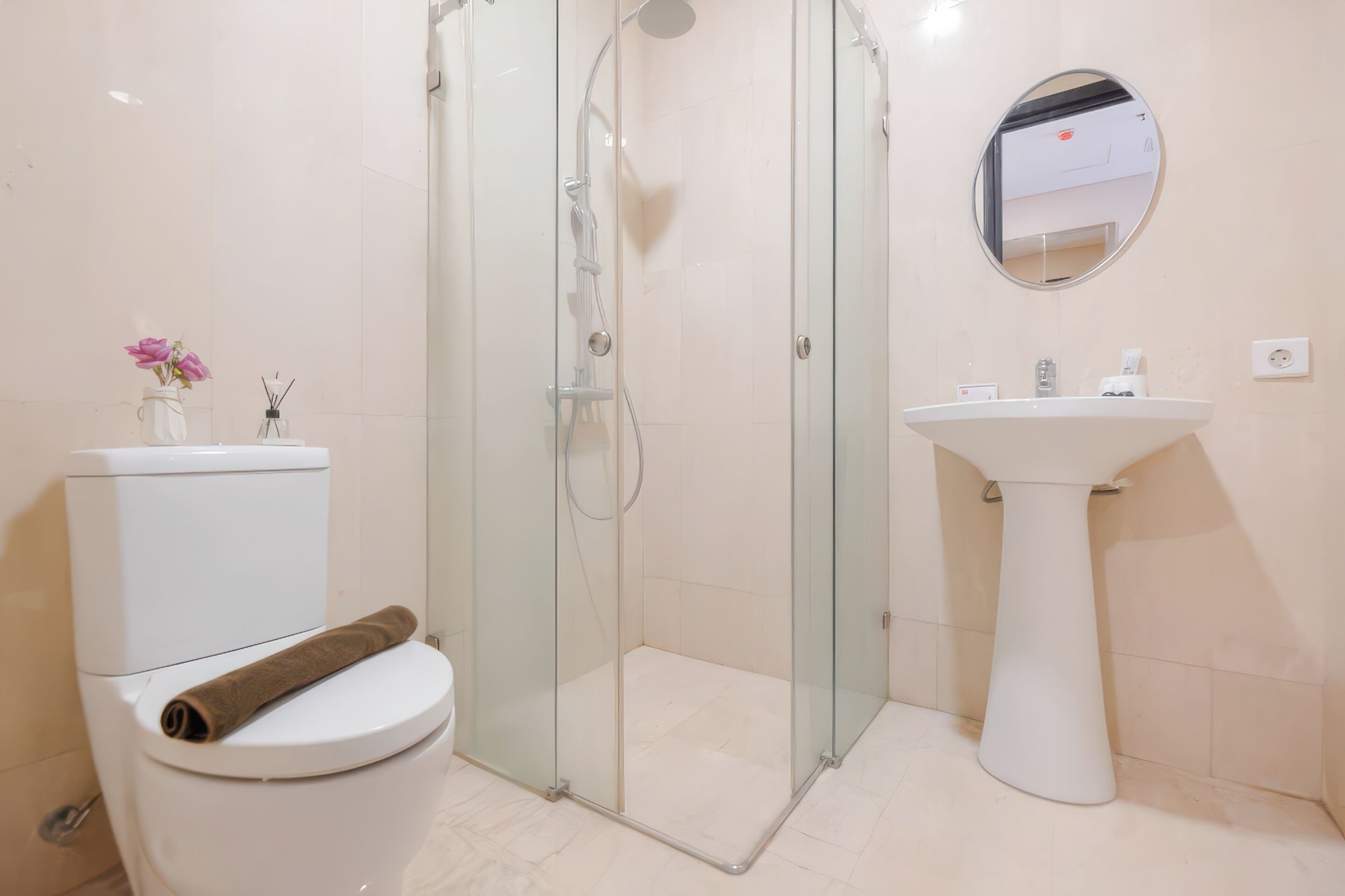 Une salle de bain avec une douche à parois de verre, des toilettes blanches, un lavabo et un miroir.