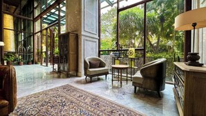 A spacious lobby with a large, ornate rug, comfortable seating, and a view of lush greenery outside. - Sudirman Suites Apartment Jakarta (Jakarta)