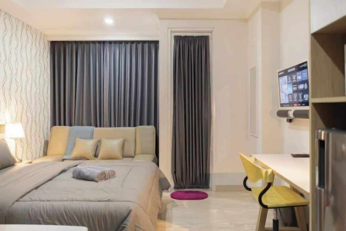 Une chambre d’hôtel avec un lit, un bureau, une chaise, une télévision et des rideaux.