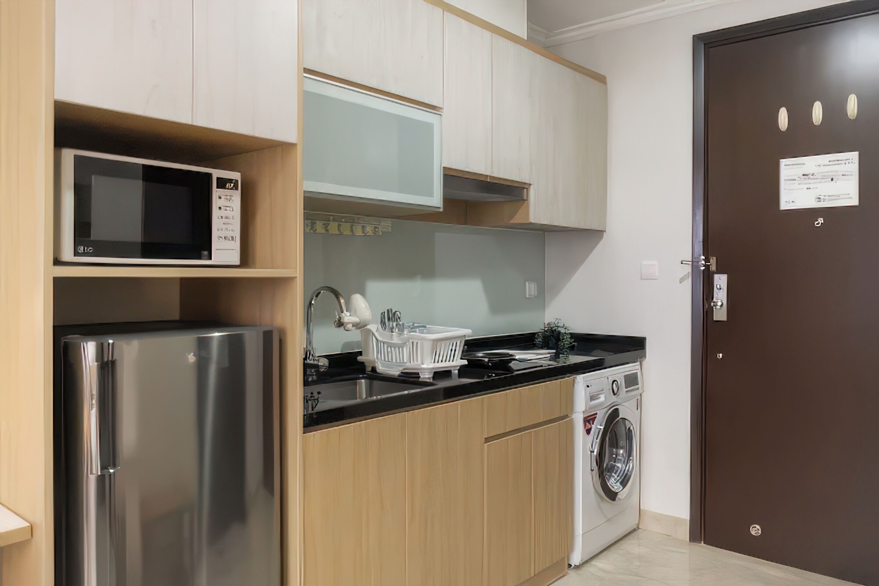 Cocina compacta con refrigerador de acero inoxidable, microondas, lavadora y lavaplatos.