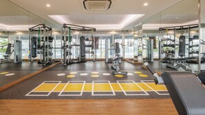 Une salle de sport moderne avec des murs recouverts de miroirs, divers appareils d’exercice et un sol à motifs.