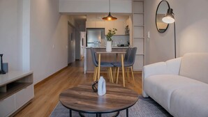 Un soggiorno moderno con un divano, un tavolo da pranzo con sedie, una cucina sullo sfondo e una lampada a sospensione.