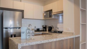 Una cucina moderna con un frigorifero in acciaio inox, un forno a microonde e una cucina a gas. C'è un piano di lavoro in legno e un lavello con un rubinetto.