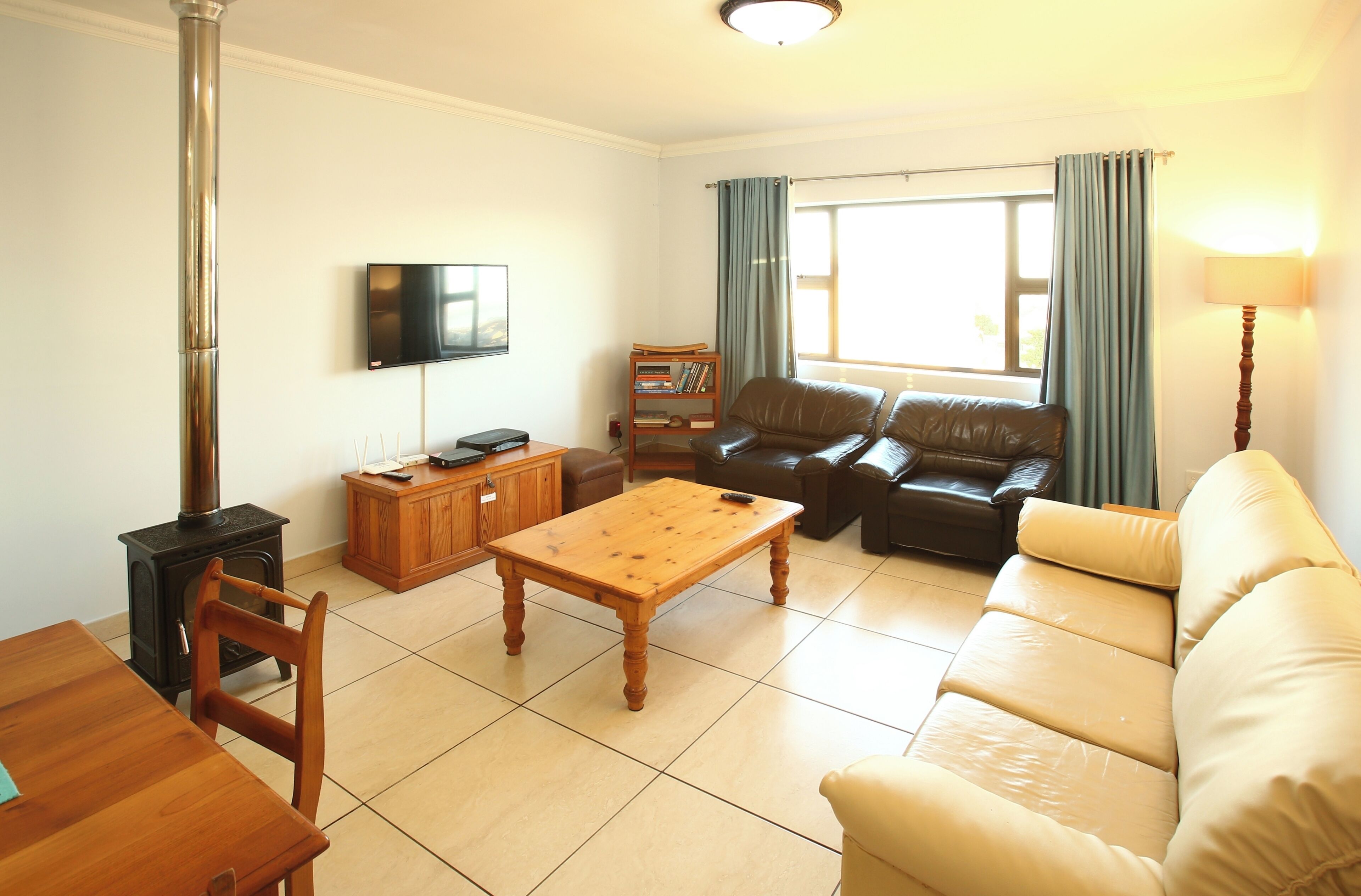 A living room with a wooden table, leather sofa, and a television on the wall.