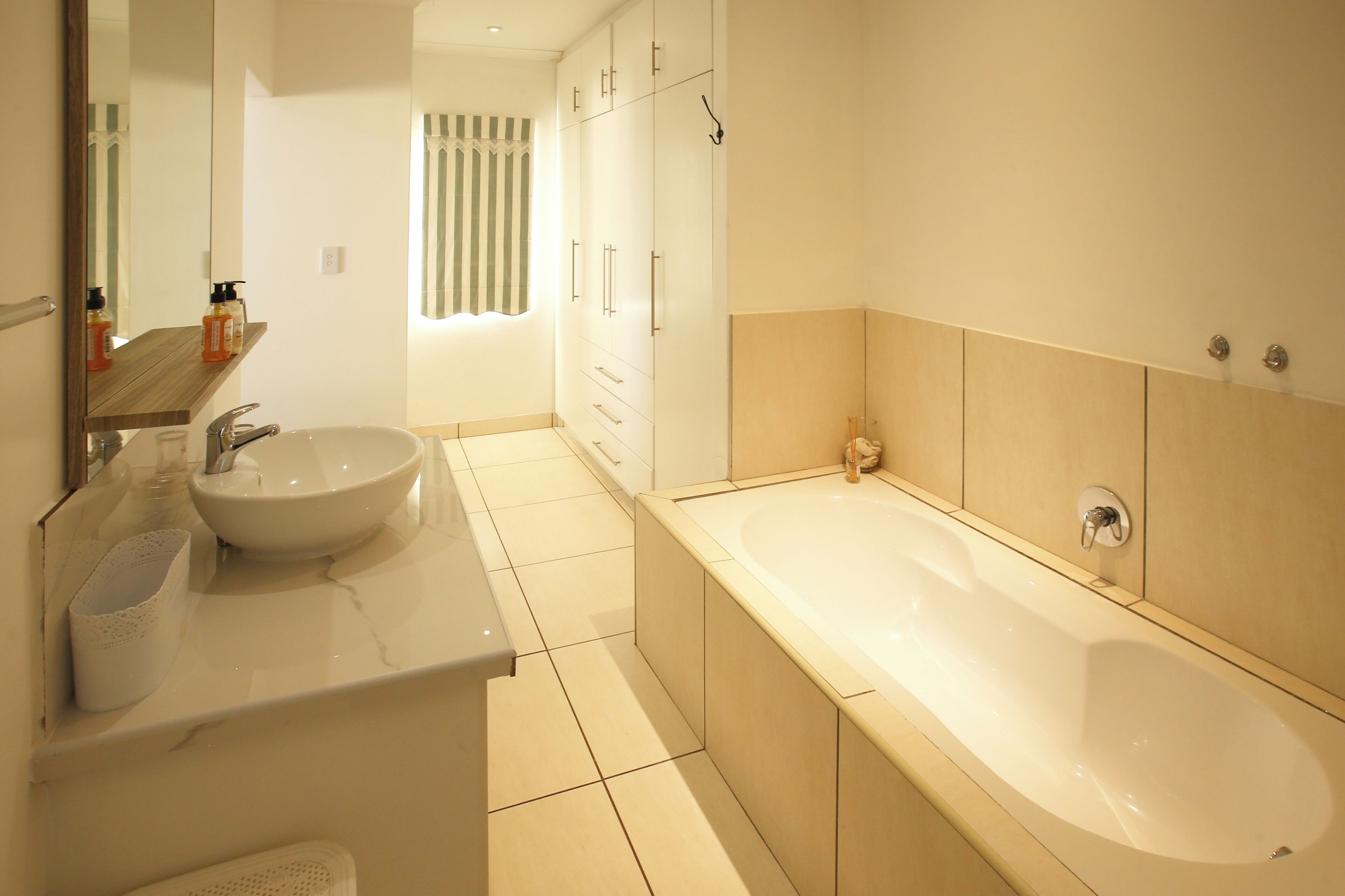 Un baño moderno con lavamanos, espejo y bañera.