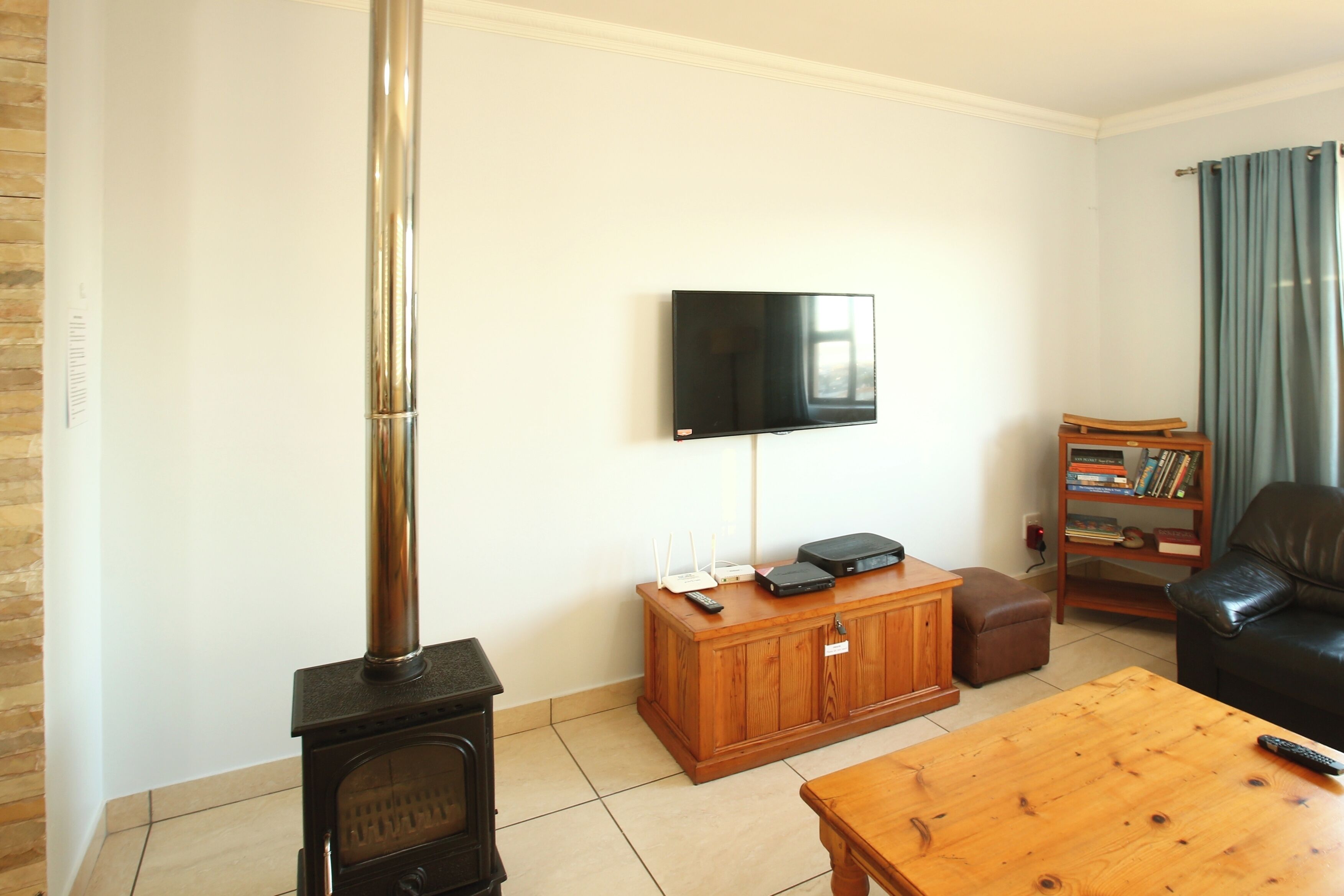 A living room with a fireplace, a television mounted on the wall, a wooden cabinet, a leather sofa, and a coffee table.