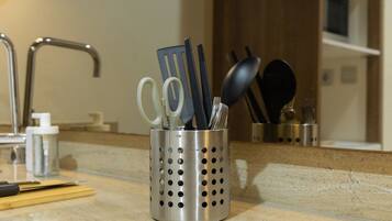 Un plan de travail de cuisine avec un porte-ustensiles en acier inoxydable contenant des ciseaux, une spatule et une cuillère.