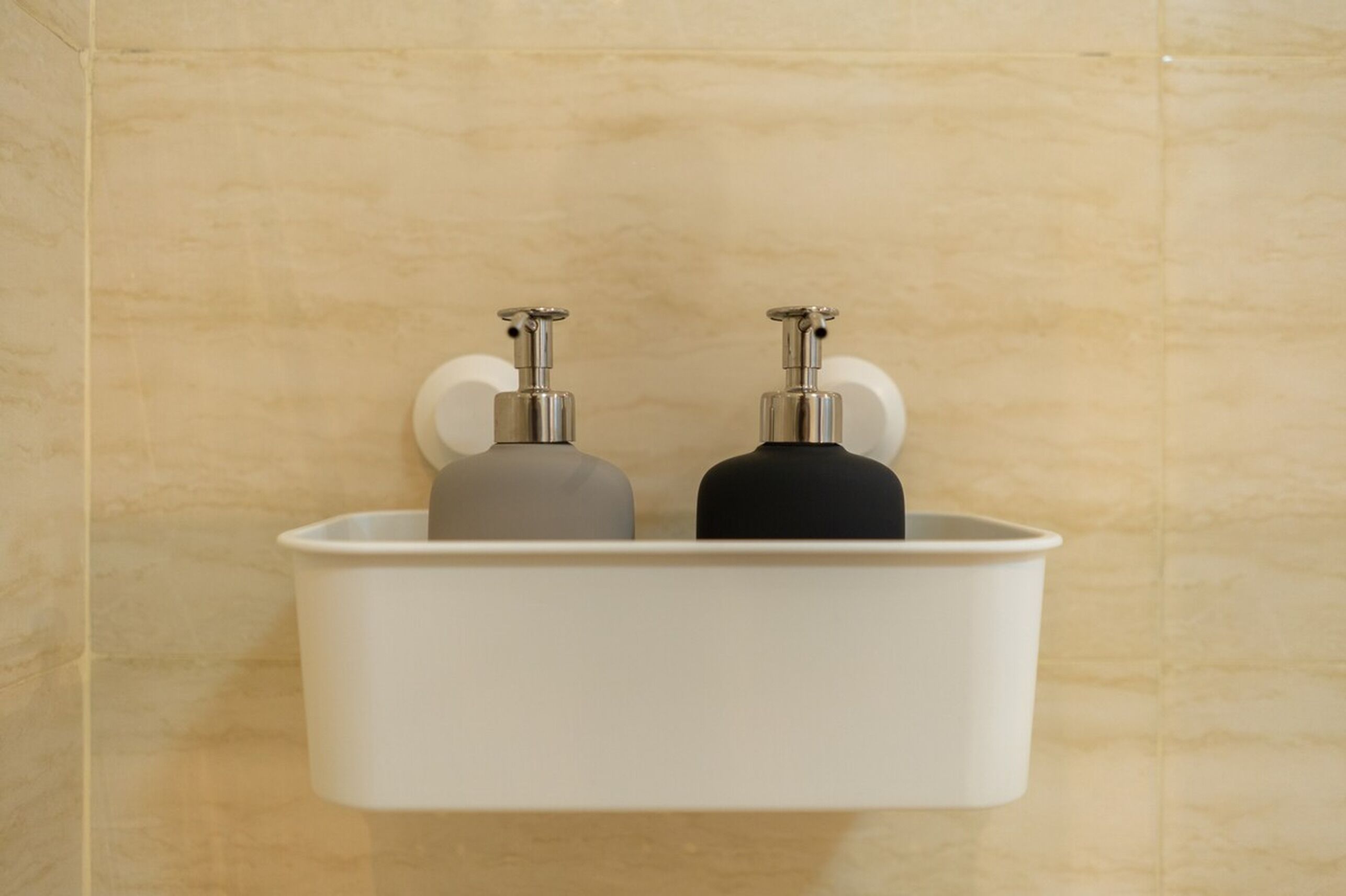 Un baño con lavamanos blanco y dos dispensadores de jabón.