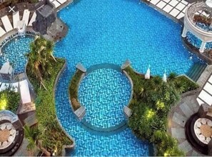 Ein großes Hallenbad mit mehreren kleineren Becken und umgebender Bepflanzung.