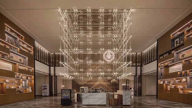 A spacious lobby with a modern chandelier, marble flooring, and wooden shelving with various items. - Wanda Moments Alar (Aral City)
