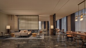 A modern hotel lobby with a seating area, a dining table, and a large window with curtains. - Wanda Moments Alar (Aral City)