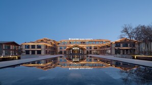 A modern hotel with a central reflective pool, multiple buildings, and a clear sky. - Wanda Moments Alar (Aral City)