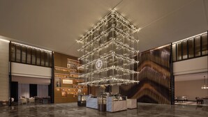 A modern lobby with a central chandelier, seating areas, and a reception desk. - Wanda Moments Alar (Aral City)