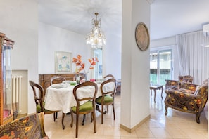 A traditional dining area with a wooden table and chairs, a chandelier, and a decorative mirror.